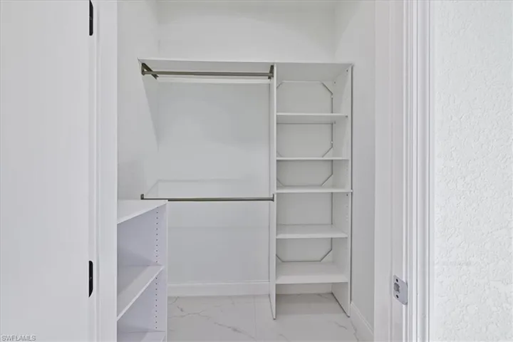 Walk in closet featuring light marble finish flooring