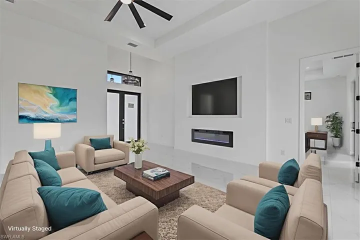 Living area featuring a fireplace, a high ceiling, marble tiled flooring, and a ceiling fan
