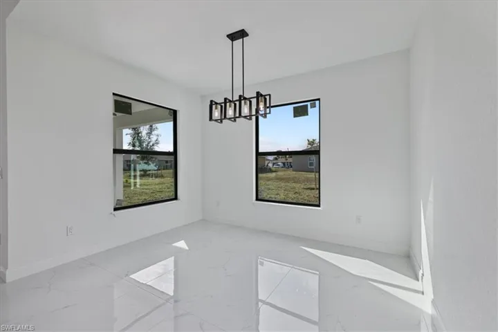 Unfurnished dining area featuring a chandelier and light marble finish floors