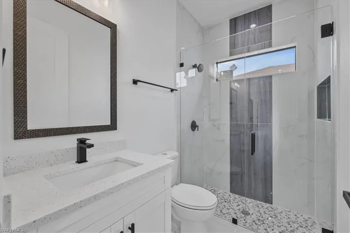Full bath featuring vanity and a marble finish shower