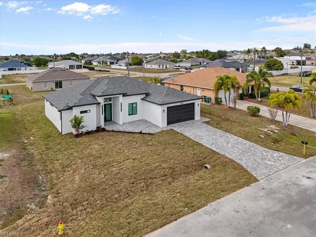 View of front facade featuring stucco siding, a residential view, a front yard, and roof with shingles