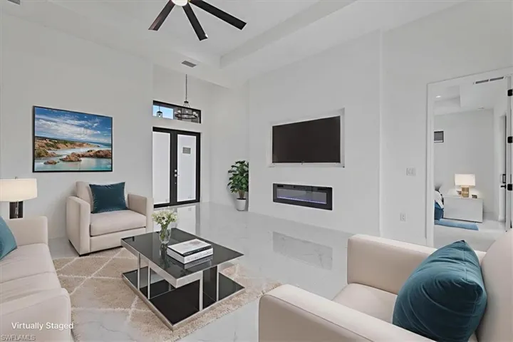 Living area featuring a glass covered fireplace, a high ceiling, and a ceiling fan