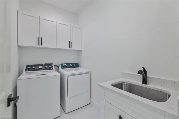 Laundry area featuring cabinet space, independent washer and dryer, and light marble finish flooring