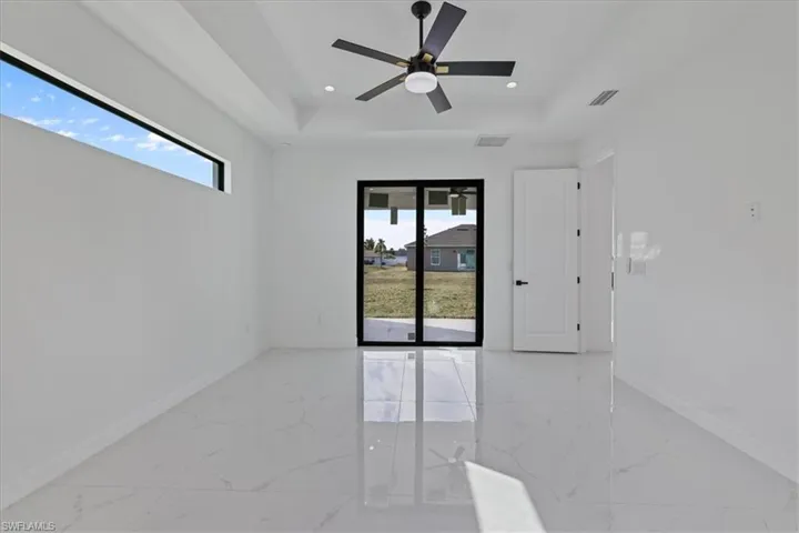 Empty room with light marble finish floors, a raised ceiling, a ceiling fan, and recessed lighting