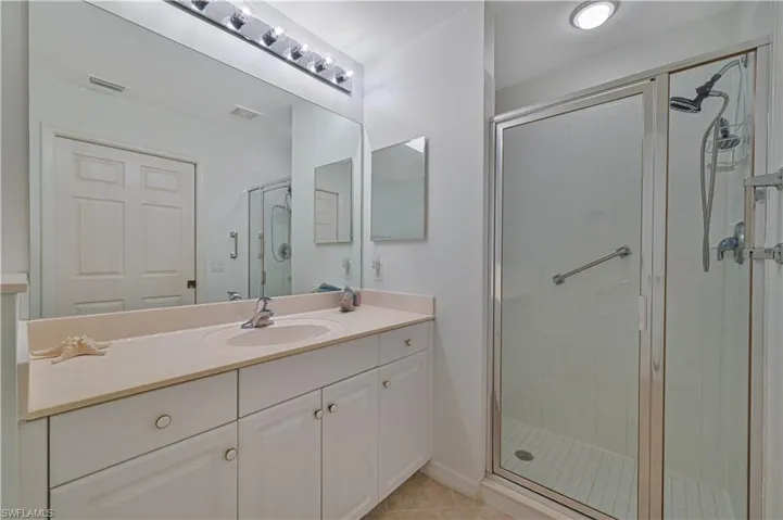 The ensuite bathroom features additional cabinets, a countertop-wide mirror, detachable shower head, and pocket door.