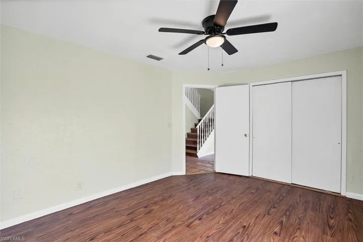Downstairs bedroom with dark wood-type flooring, a ceiling fan, and a closet