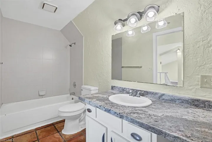 Full bathroom with a textured wall, vanity, and tub / shower combination