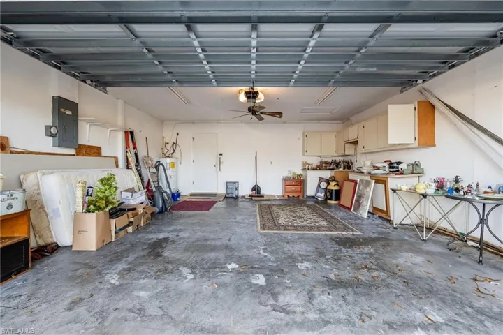 Garage with electric panel, ceiling fan, electric water heater, and a garage door opener