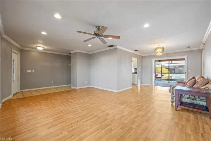 Unfurnished living room with a chandelier, crown molding, light wood-style floors, and ceiling fan