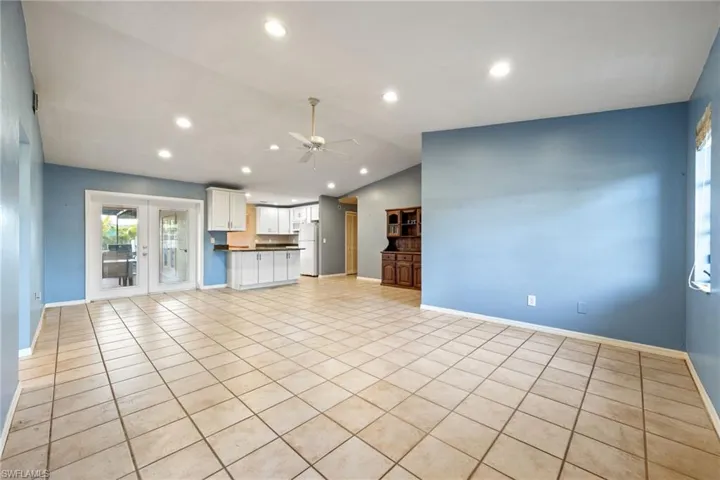 Unfurnished living room featuring ceiling fan, recessed lighting, light tile patterned floors, french doors, and vaulted ceiling