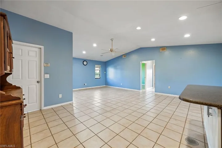 Unfurnished living room with a ceiling fan, vaulted ceiling, light tile patterned floors, and recessed lighting