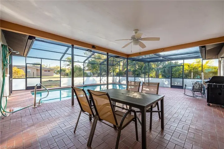 Sunroom featuring a ceiling fan, a pool, a patio, and outdoor dining space