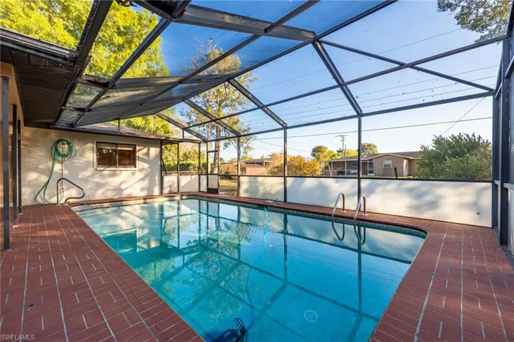 Swimming pool with a sunroom, glass enclosure, and a patio