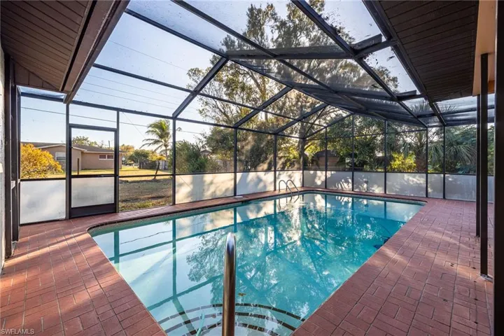 Swimming pool featuring a sunroom, a lanai, and a patio
