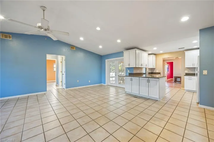 Kitchen with a peninsula, open floor plan, lofted ceiling, white cabinets, and light tile patterned floors