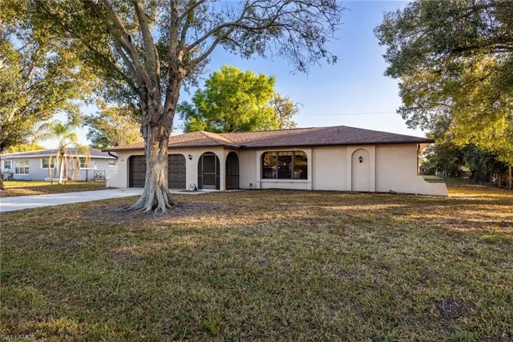 View of front facade with driveway, a front yard, a garage, and stucco siding