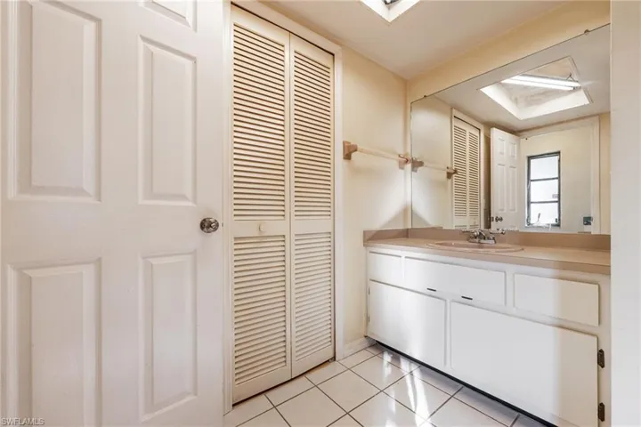 Bathroom with a closet, vanity, and light tile patterned flooring