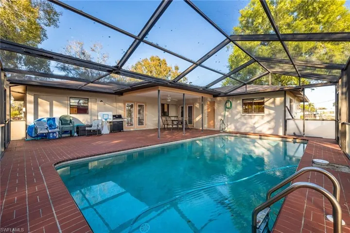 Outdoor pool featuring a sunroom, french doors, a lanai, and a patio
