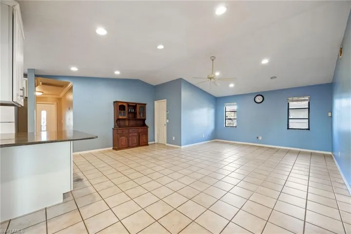 Unfurnished living room featuring vaulted ceiling, ceiling fan, light tile patterned floors, and recessed lighting