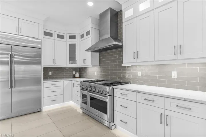 Kitchen featuring recessed lighting, white cabinets, appliances with stainless steel finishes, a large fireplace, and open floor plan