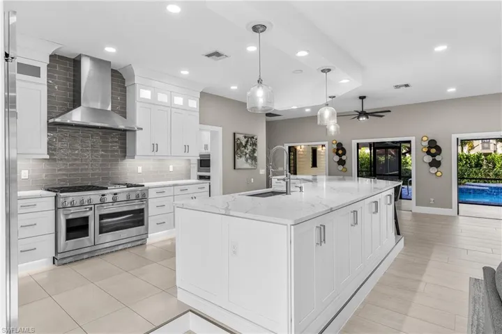 Kitchen with light countertops, open floor plan, white cabinetry, built in refrigerator, and recessed lighting