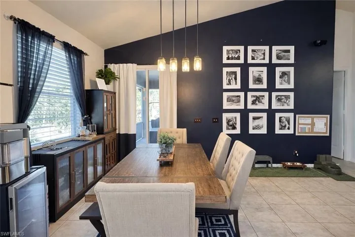 Dining space featuring lofted ceiling, beverage cooler, and light tile patterned flooring