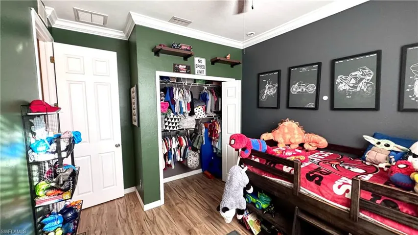 Bedroom with crown molding, wood finished floors, and a closet