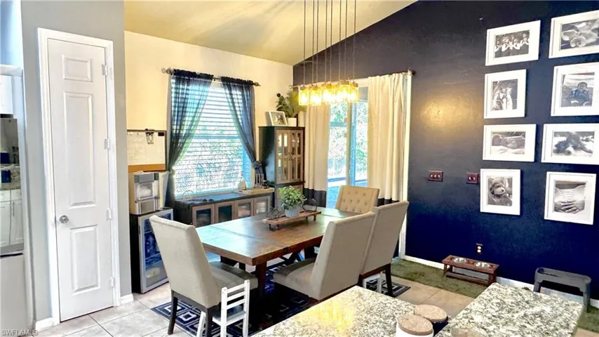 Dining area with lofted ceiling, wine cooler, and light tile patterned floors