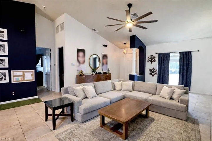 Living room with a ceiling fan, arched walkways, high vaulted ceiling, and light tile patterned floors