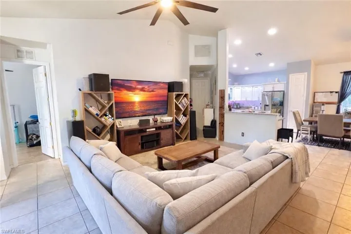 Living room featuring vaulted ceiling, light tile patterned floors, a ceiling fan, and recessed lighting