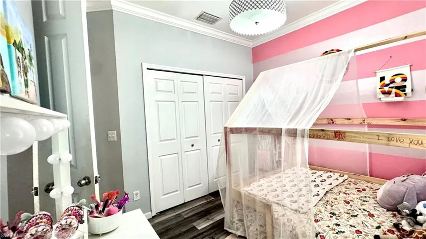 Bedroom featuring ornamental molding, dark wood finished floors, and a closet