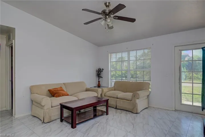 Living room featuring a wealth of natural light, marble finish floor, and a ceiling fan
