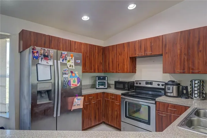 Kitchen featuring a sink, light countertops, appliances with stainless steel finishes, recessed lighting, and vaulted ceiling