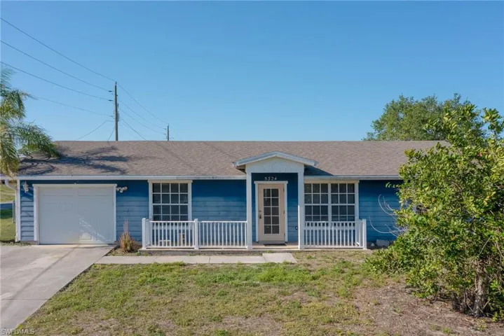 Ranch-style house with a garage, roof with shingles, driveway, and covered porch