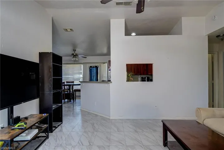 Living area with visible vents, ceiling fan, and marble finish floor