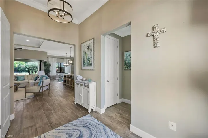 Corridor with a chandelier, dark wood finished floors, ornamental molding, and baseboards