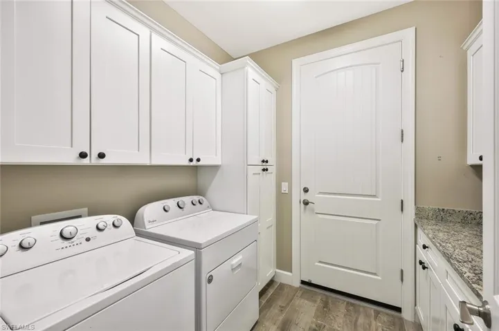 Laundry area with wood finished floors, washing machine and clothes dryer, and cabinet space