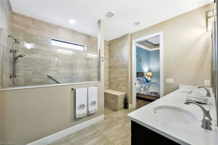 Bathroom with walk in shower, visible vents, a sink, and ensuite bathroom