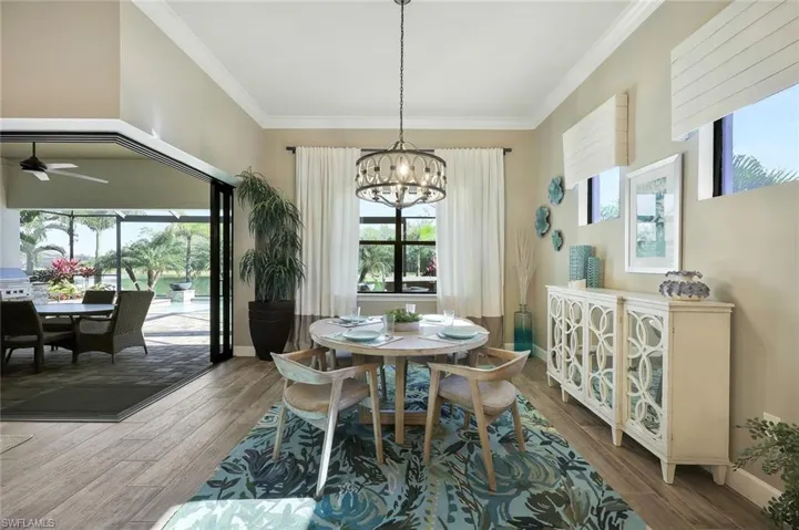 Dining space with ornamental molding, ceiling fan with notable chandelier, baseboards, and wood finished floors