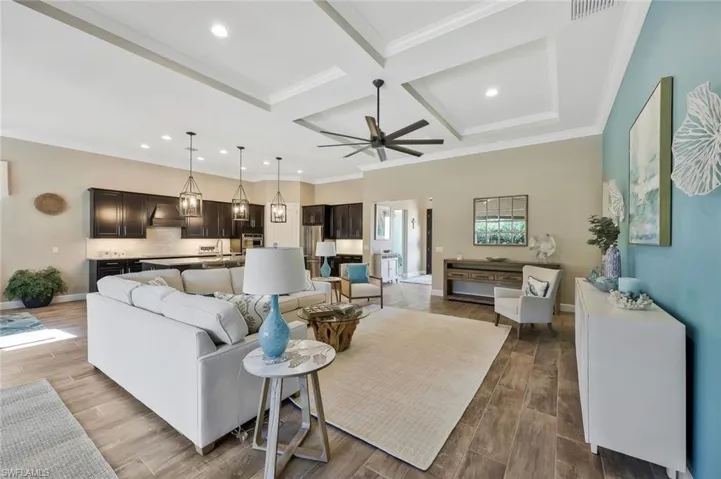 Living area with coffered ceiling, wood finished floors, baseboards, beam ceiling, and crown molding