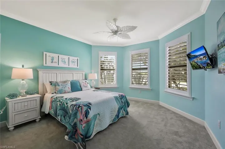 Carpeted bedroom with crown molding, baseboards, and ceiling fan