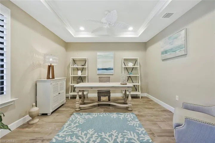 Sitting room featuring baseboards, visible vents, ornamental molding, a tray ceiling, and light wood-type flooring