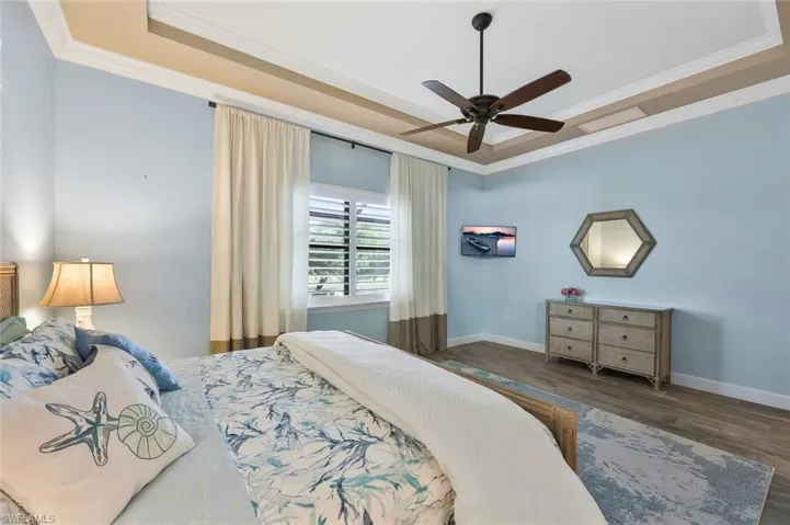 Bedroom featuring ornamental molding, a raised ceiling, baseboards, and wood finished floors
