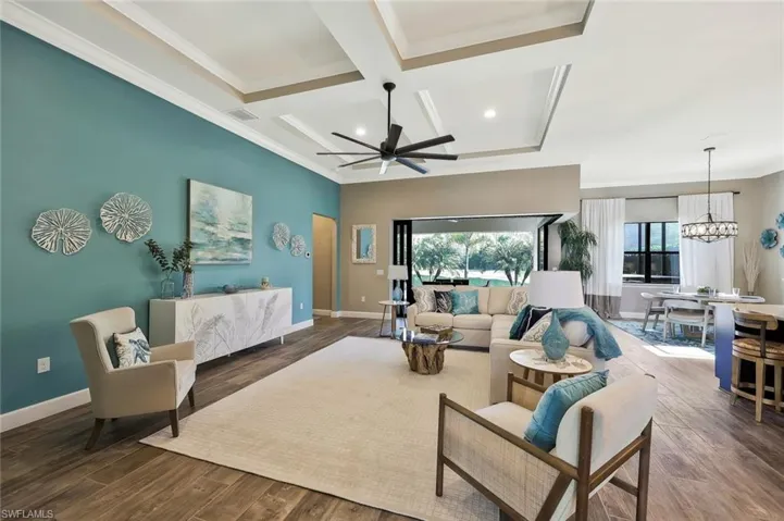 Living room with coffered ceiling, wood finished floors, visible vents, baseboards, and crown molding