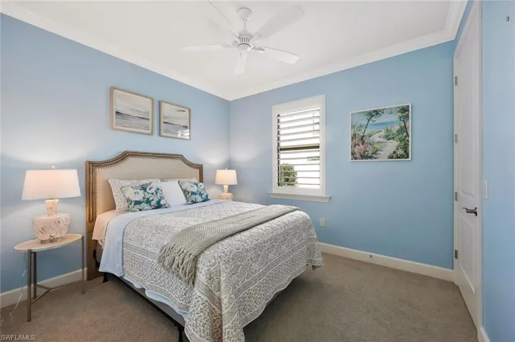 Carpeted bedroom featuring baseboards, ornamental molding, and ceiling fan