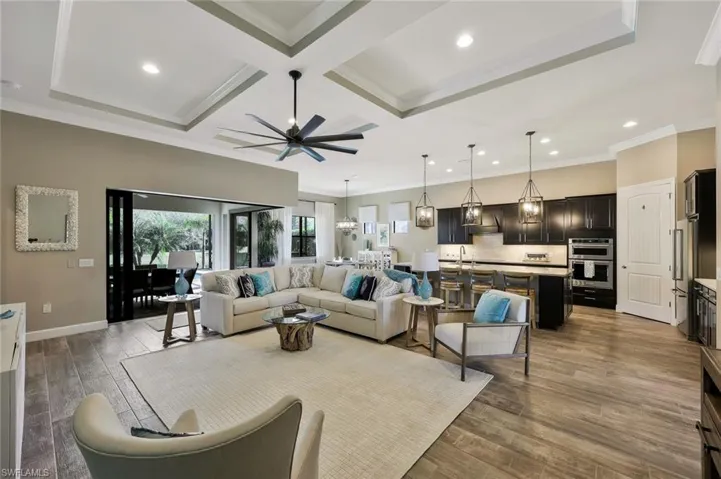 Living room with ornamental molding, coffered ceiling, wood finished floors, and baseboards