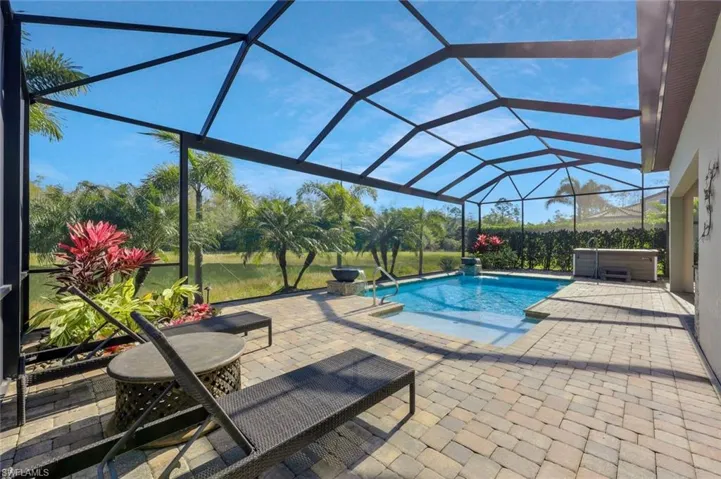 Outdoor pool featuring a patio area, a hot tub, and glass enclosure