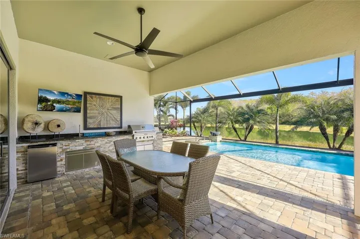 View of patio / terrace featuring grilling area, area for grilling, a ceiling fan, glass enclosure, and an outdoor pool