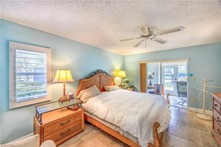 Bedroom featuring stone tile floors, access to exterior, ceiling fan, and a textured ceiling