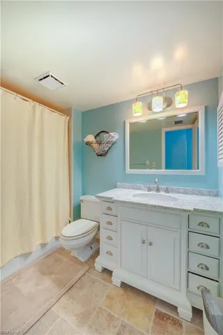 Full bathroom featuring visible vents, shower / tub combo with curtain, toilet, and vanity